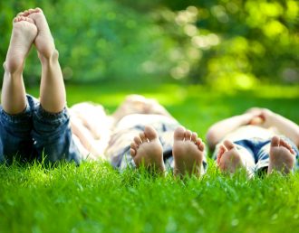 Group of happy children lying on green grass outdoors in spring park